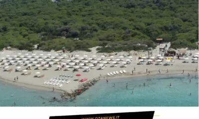 Ugento's pineta comunale (pine forest) overlooks a beach with umbrellas and people.